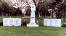 The memorial at Queen of Heaven cemetery, erected in 1960 by Monsignor Joseph Cussen. On either side of the statue of the Virgin Mary stand granite monuments engraved with the names of the three nuns and 92 children who died as a result of the Our Lady of the Angels fire. (Photo courtesy of Renee Jackson)