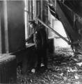A police officer looks out one of the windows where many children jumped to save their lives from the holocaust in room 208. Note the collapsed roof, an indication the fire burned the longest in and above this classroom. Room 208 was immediately adjacent to the stairwell where the fire began in the basement and traveled to the second floor. (Photo courtesy of The Catholic New World with photo research by Renee Jackson)