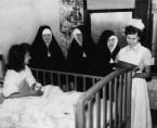Student nurse Carol Flemming checks the chart of survivor Mary Brock at St. Anne's Hospital. Looking on are, from left, Mother M. Theolinda, PHJC, Provincial Superior of Poor Handmaidens of Jesus Christ; Sister M. Joan, Administrator of St. Elizabeth hospital and Sister Almunda. (Photo courtesy of The Catholic New World with photo research by Renee Jackson)