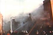 Firemen struggle to get a handle on the fire from the alley north of the school. The snorkel is shooting water into room 210 while crews on the ground attack the blaze in room 208 and the northeast stairwell. Fire can be seen through the northwest stairwell window at the far right.